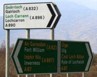 Bilingual road signs in Scotland shown in different colours.