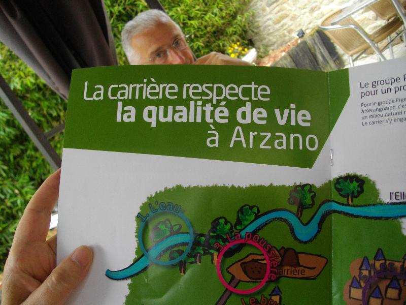 Dominique Avelange pensif avec la plaquette annonçant la carrière en premier plan.