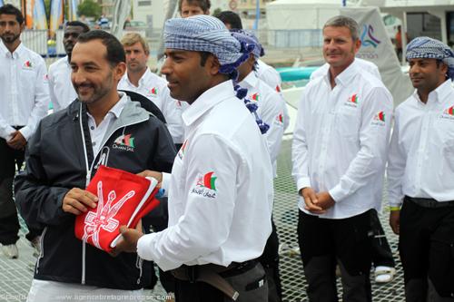 Son Altesse Sayyid Tarik bin Shabib Al Said d’Oman a offert à l’équipier de Musandam-Oman Sail Khamis Al Anbouri sous les yeux d’un nombreux public et devant le somptueux trimaran le drapeau Omanais.