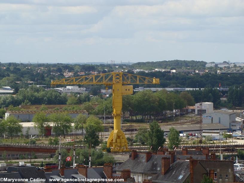 La grue Titan jaune vue de la tour du Musée Dobrée à Nantes. Éoliennes et pilônes haute tension dans le lointain. La grue Titan jaune vue de la tour du Musée Dobrée à Nantes. Éoliennes et pilônes haute tension dans le lointain.