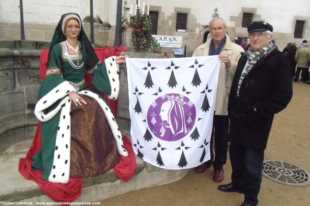 Anna en robe d'Anne de Bretagne avec Jacky Flippot (Blain) et Jakez Lhéritier (Saint-Nazaire) du Comité Anne de Bretagne 2014 présentent la bannière Anne de Bretagne lors du <b>Premier Jour</b> du timbre devant le puits dans la cour du château des ducs de Bretagne à Nantes.