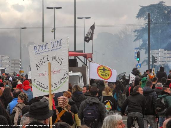 16h16. Pancarte "Bonne Dame, aidez-nous à garder nos landes", et drapeau corsaire au fond. La manifestation est très rassembleuse, avec un public mélangé. Manifestation anti-aéroport à Nantes le 22 février 2014. 16h16. Pancarte "Bonne Dame, aidez-nous à garder nos landes", et drapeau corsaire au fond. La manifestation est très rassembleuse, avec un public mélangé. Manifestation anti-aéroport à Nantes le 22 février 2014.